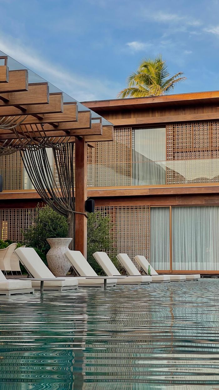 Elegant luxury resort with poolside chairs under a blue sky, perfect for relaxation.