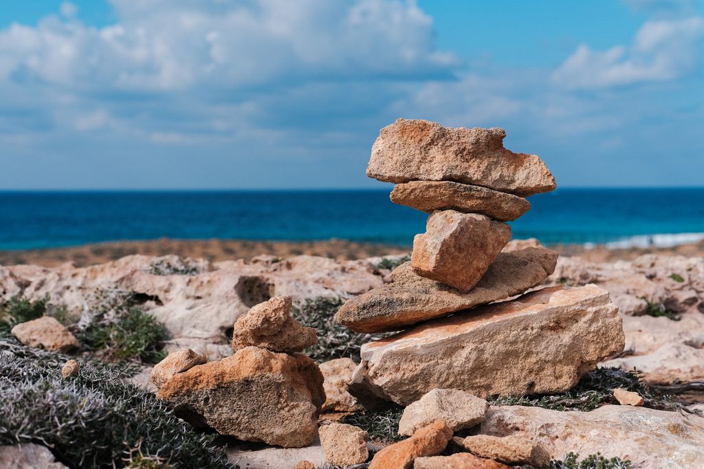 Serene view of balanced stones on rocky coast with blue sea and sky in Cyprus.