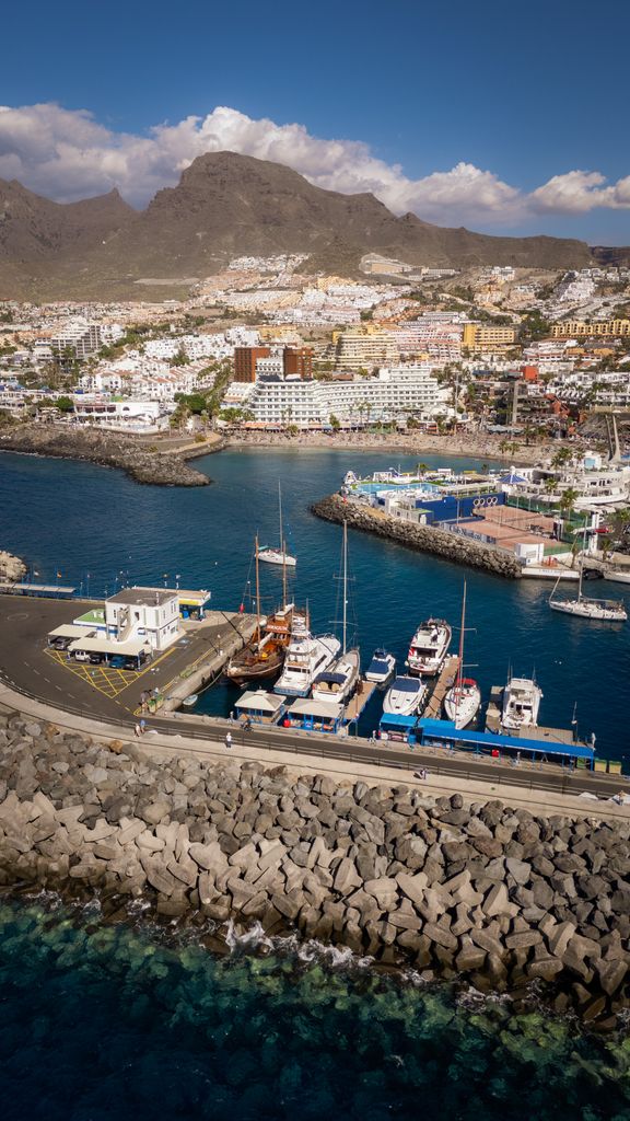 Stunning aerial photograph of Los Cristianos harbor in Tenerife, showcasing boats and coastal scenery.